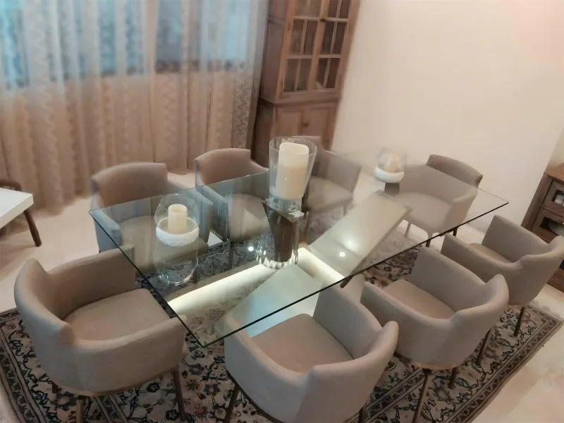 Dining room with a glass table and upholstered chairs by Yamout